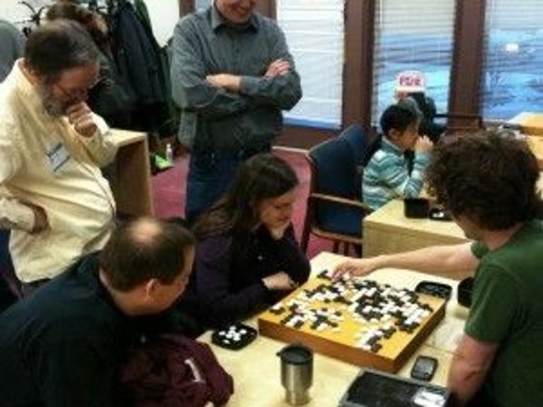 A crowd gathers around a game at Barber’s Dec. 11, 2010, Chicago Winter Tournament. Twenty-nine players attended despite severe weather warnings. Photo by Mark Rubenstein. Source: https://aga-news-archive-viewer.azurewebsites.net/api/news-archive/article/7314.